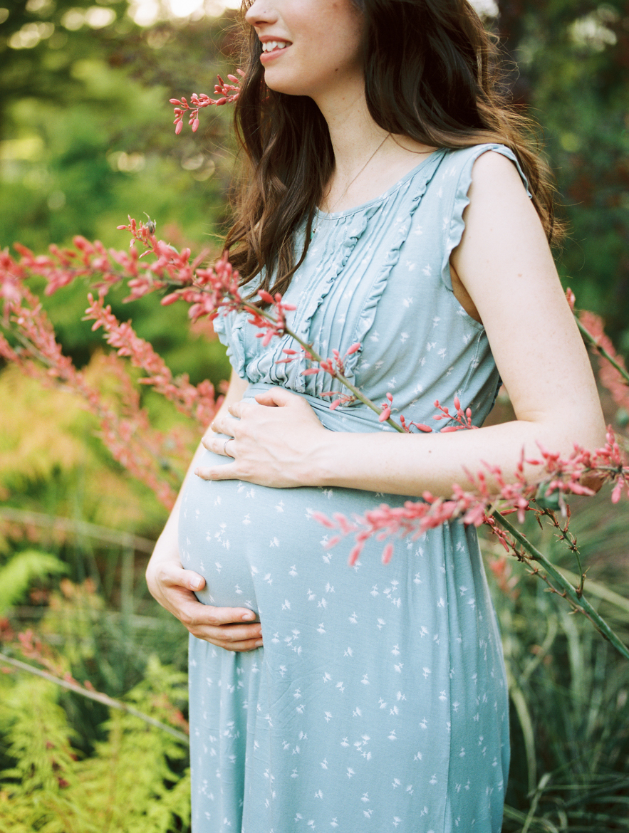 detail of woman in flowers holding pregnant belly