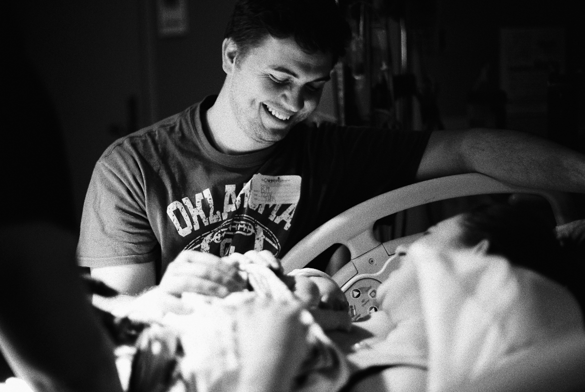 father smiling at newborn baby