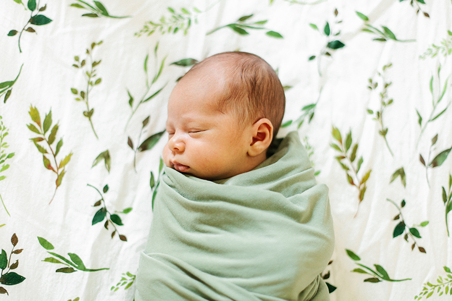 swaddled newborn laying on bed
