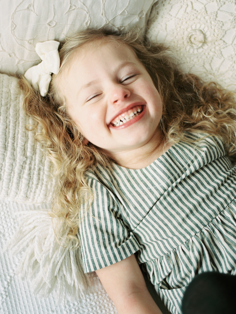 toddler girl laying on bed laughing