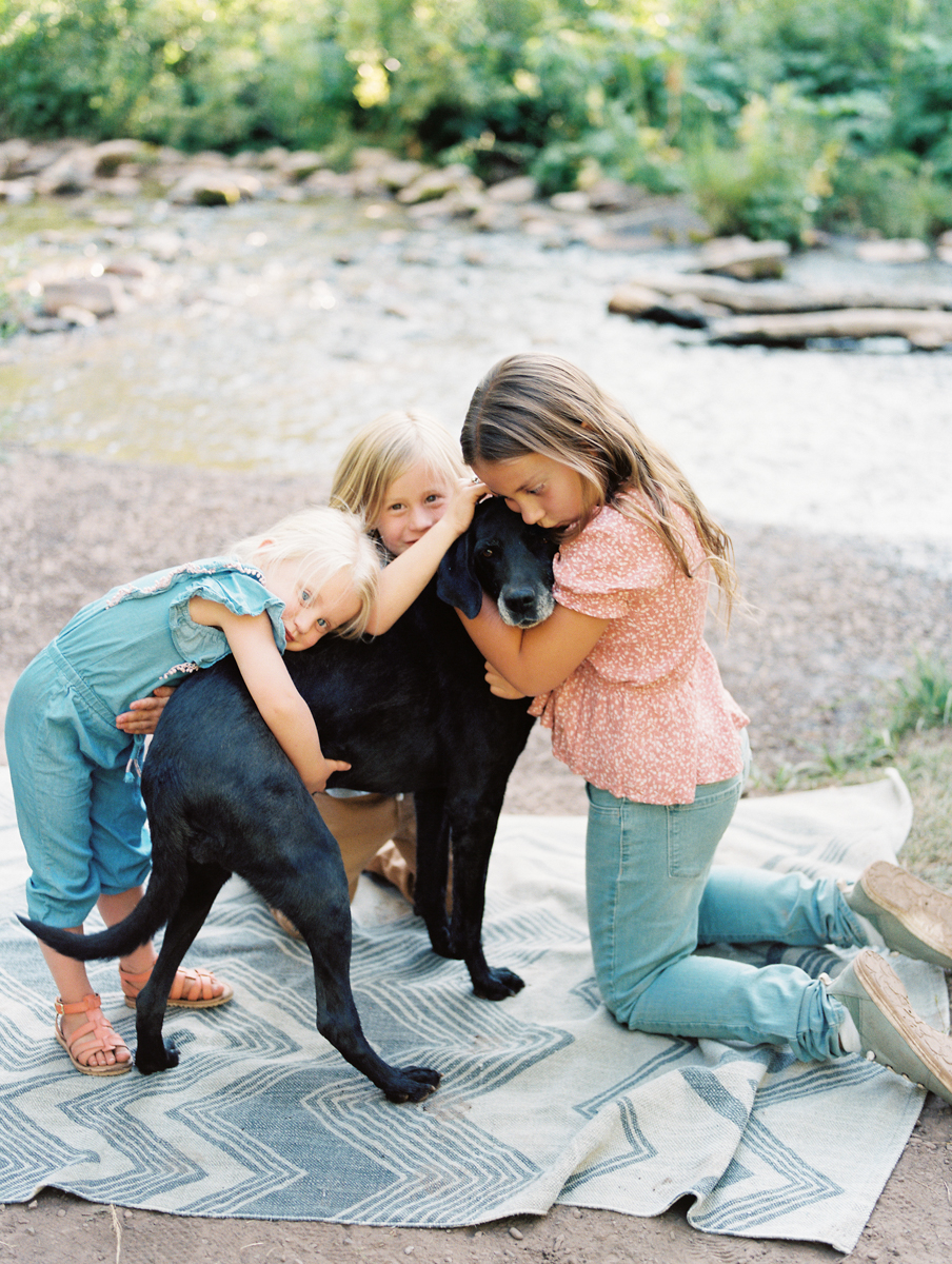 three children hugging dog