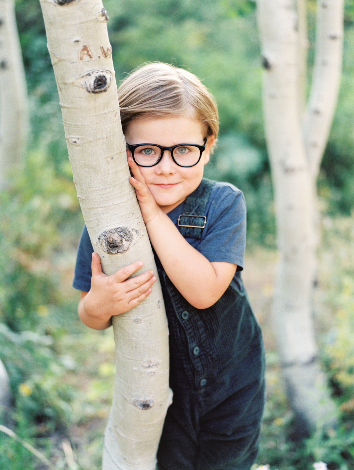 portrait of little boy leaning on tree