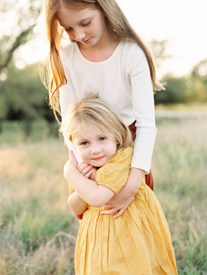 older sister hugging younger sister