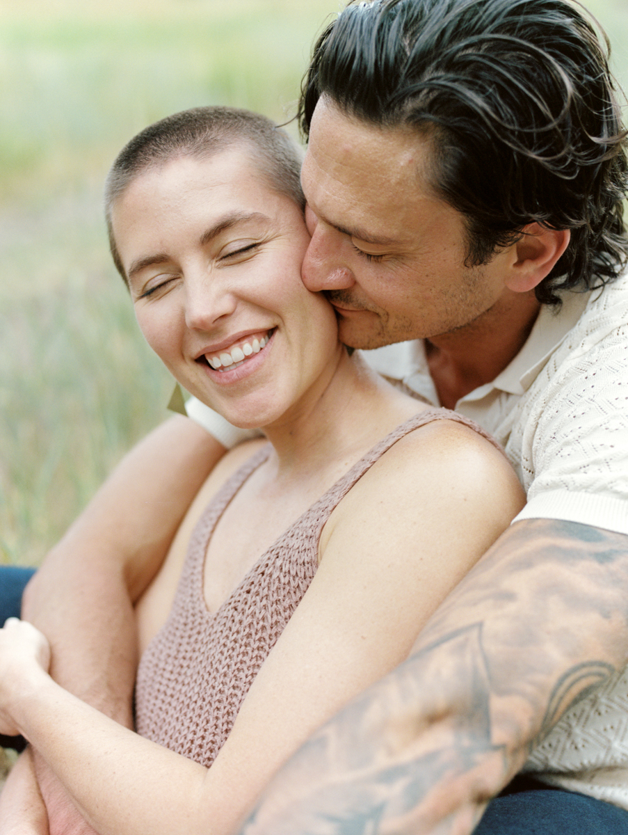 husband kissing wife's cheek from behind