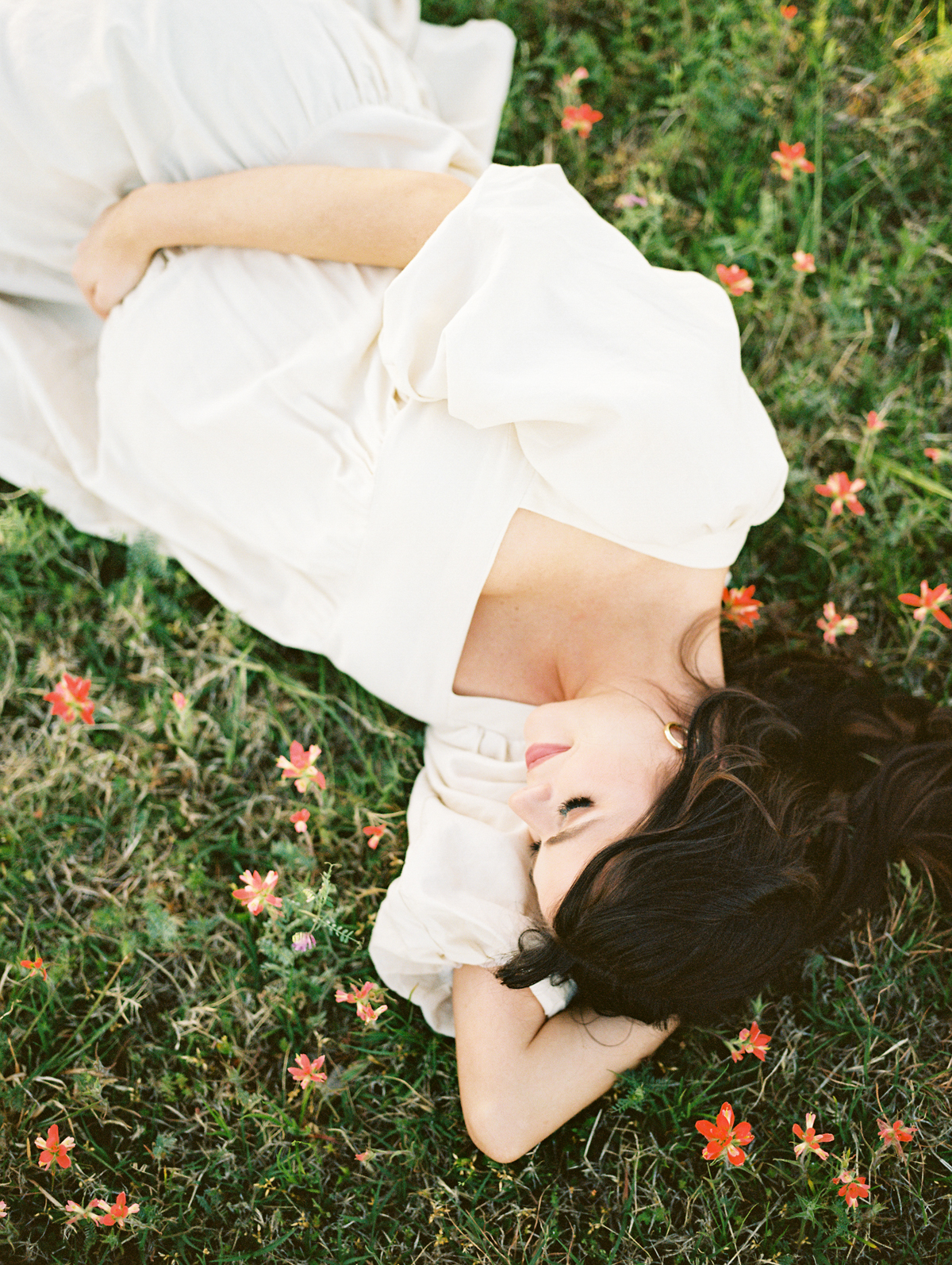 expectant mother laying in a field of red wildflowers