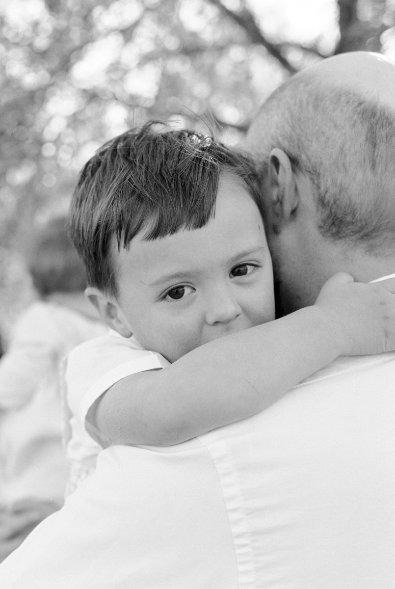 black and white photo of little boy with his arms wrapped around his dad's neck