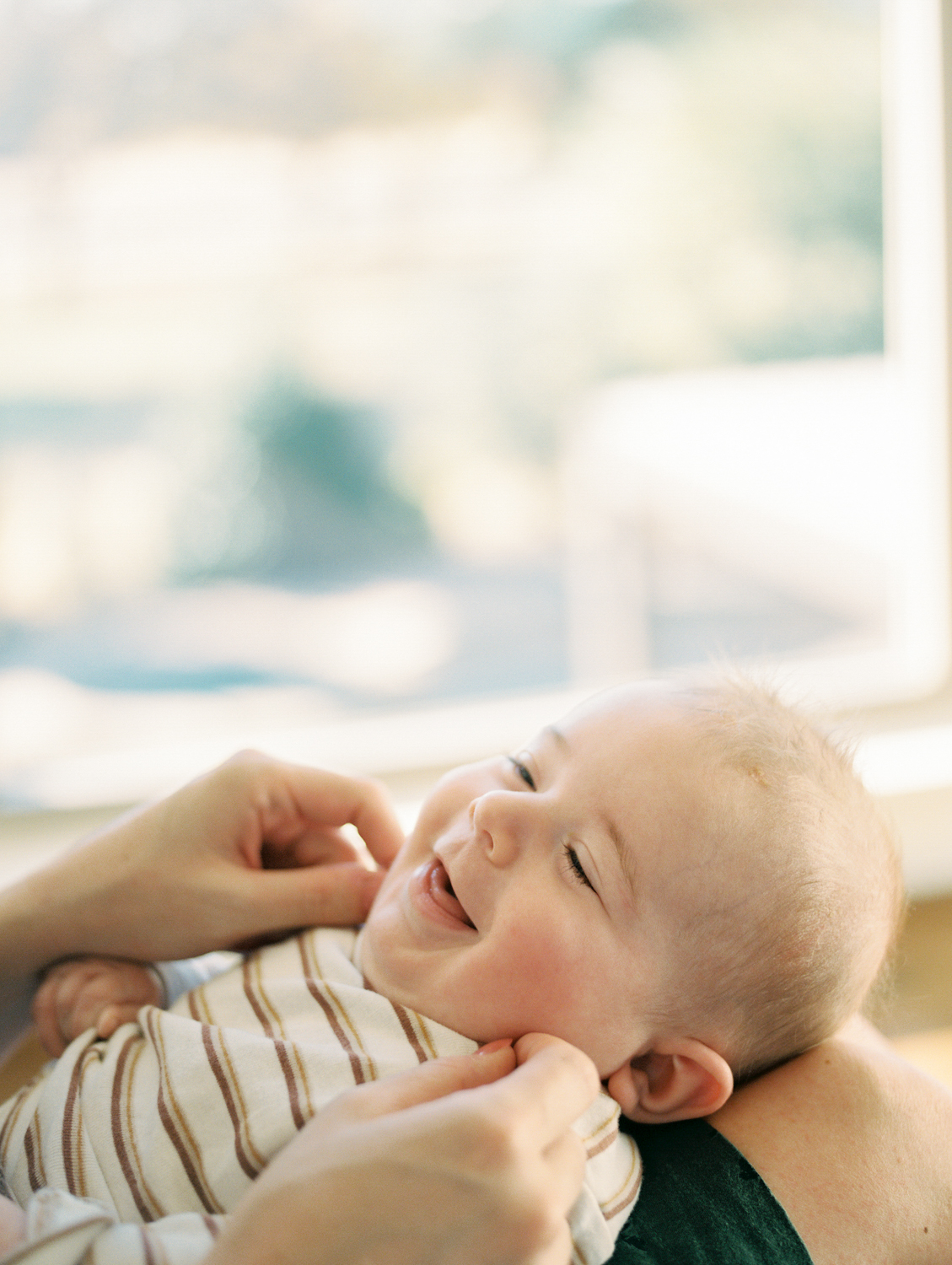 Young child smiling in mother's lap during a candid outdoor family photos in Edmond, OK.