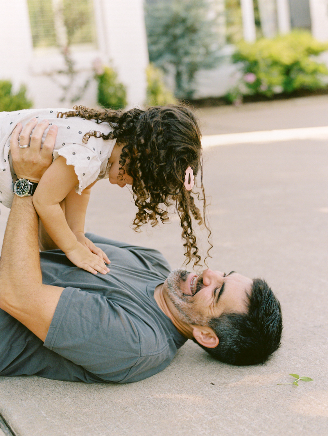 dad laying on the ground holding his daughter up in the air