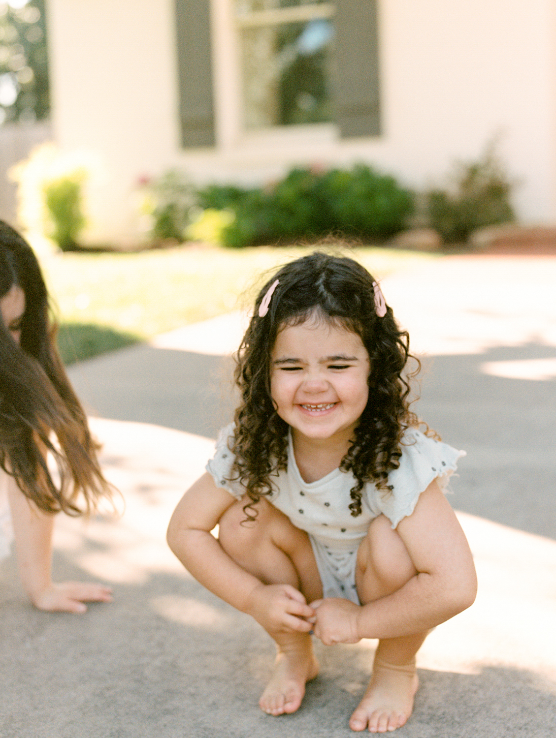 young girl smiling while playing with sidewalk chalk