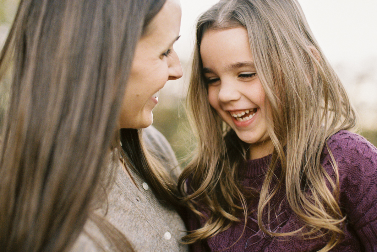 portrait of three young children tucked between their mom and dad