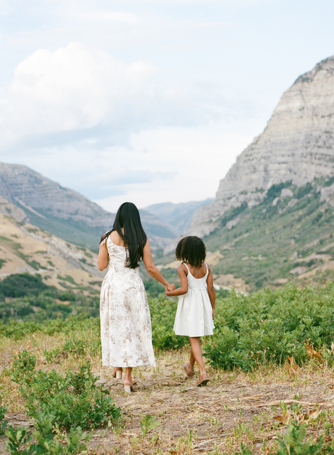 mother and daughter walking away from the camera holding hands
