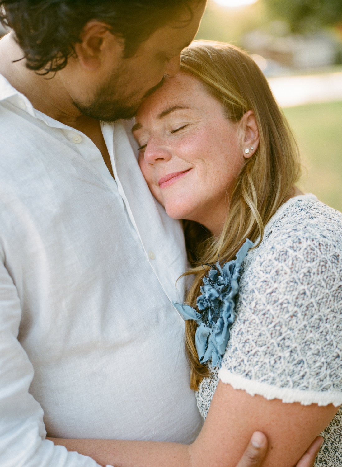 father kissing mother's forehead and mother relaxing into him