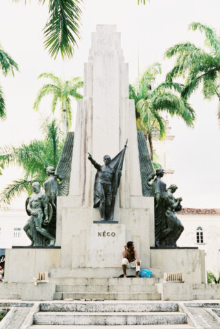 man sitting below statue in brazil